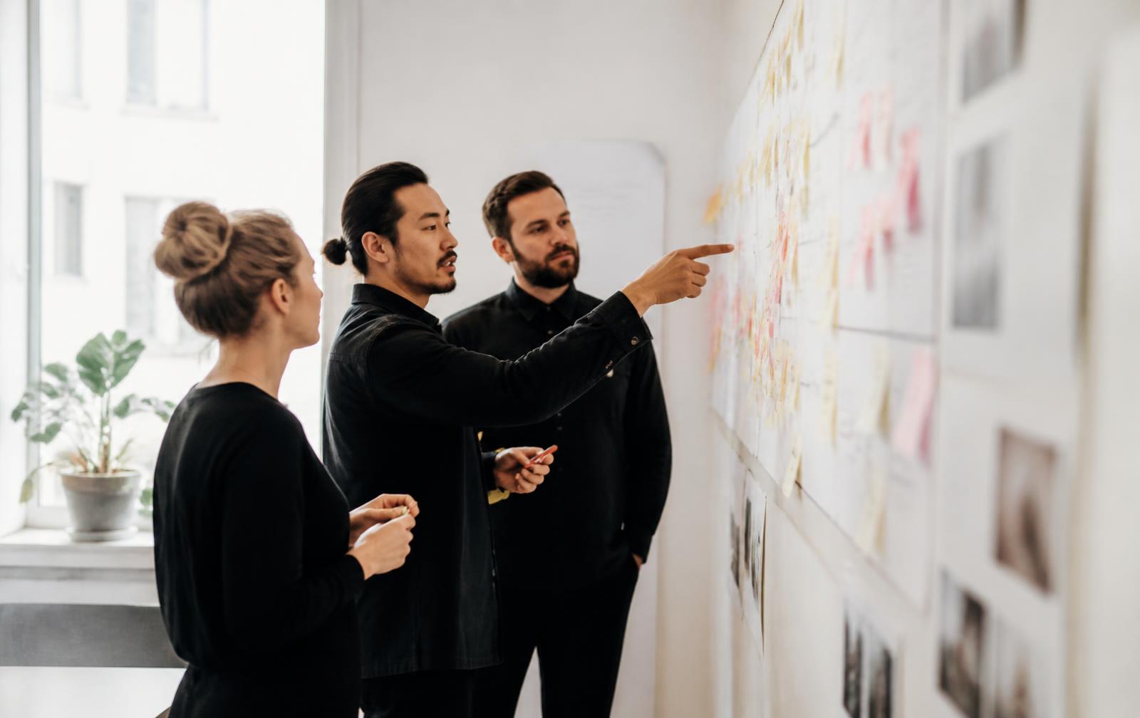 Colleagues reviewing a wall of process diagrams during a working session